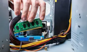 Dłoń instaluje moduł pamięci RAM, kluczowy element do czego służy szybkie przetwarzanie danych w komputerze.
