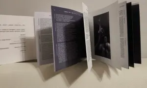 Otwarta książeczka z tekstami piosenek, w tym "Lowkey feat. Tony Kilo". Widoczna sylwetka artysty.