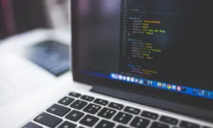Kod źródłowy na ekranie laptopa, przypominający instalację linux snap. Widoczna klawiatura i fragment ekranu z kodem.