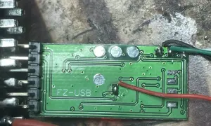 Zielona płytka drukowana z oznaczeniem "FZ-USB", prawdopodobnie moduł ELM327. Widać przewody i złącza, gotowe do instalacji sterowniki.
