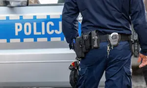 Policjant w pełnym rynsztunku, z pistoletem i kajdankami, stoi obok radiowozu. Wszystko wygląda na rutynową kontrolę, ale czy na pewno? Czasem nawet najbardziej oczywiste sygnały mogą okazać się fałszywym pozytywem.