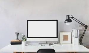 Nowoczesne biurko z monitorem, klawiaturą i lampką. Idealne miejsce do pracy zdalnej, gdzie pulpit zdalny pozwoli Ci połączyć się z biurem.