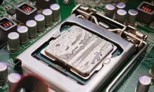 Procesor z zaschniętą pastą termoprzewodzącą, gotowy do testu chłodzenia CPU. Widoczne kondensatory i elementy płyty głównej.