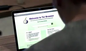 Osoba korzysta z laptopa z otwartą stroną powitalną przeglądarki **Tor Browser**, która umożliwia anonimowe przeglądanie Internetu.