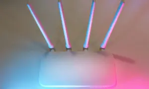 Biały router z czterema antenami, podświetlony na niebiesko i różowo. Kluczowy element zabezpieczenia sieci.