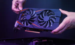 Dwie ręce trzymają kartę graficzną z dwoma wentylatorami, gotową do montażu. Zastanawiasz się, jaka karta graficzna do laptopa będzie najlepsza?