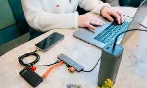 Kobieta pracuje na laptopie, podłączając telefon, dysk zewnętrzny i kartę SD do huba USB 3.2 Gen. 1.