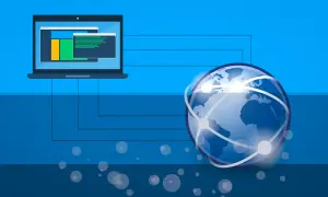 Laptop połączony z globem, symbolizującym sieć. Zastanawiasz się, co to IP? To Twój adres w tej globalnej sieci.