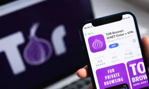 Aplikacja TOR Browser na telefonie, obok logo TOR na ekranie laptopa. Dowiedz się, jak wejść do darknetu, korzystając z tej przeglądarki.