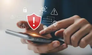 Dłonie trzymające smartfon, nad którym unoszą się ikony symbolizujące bezpieczeństwo i ochronę przed zagrożeniami. To pokazuje, co to jest antywirus w praktyce.