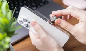 Dłoń wkłada kartę SIM do telefonu, przygotowując się do zmiany operatora lub konfiguracji nowego urządzenia.