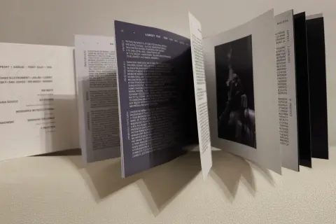 Otwarta książeczka z tekstami piosenek, w tym "Lowkey feat. Tony Kilo". Widoczna sylwetka artysty.