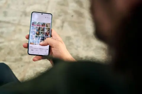 Dłoń trzyma smartfon z galerią zdjęć. Dbanie o ochronę prywatności danych jest kluczowe.