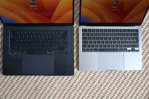 Dwa laptopy MacBook Air, jeden ciemny, drugi srebrny, leżą obok siebie. Ich niska waga sprawia, że są idealne do pracy w podróży.