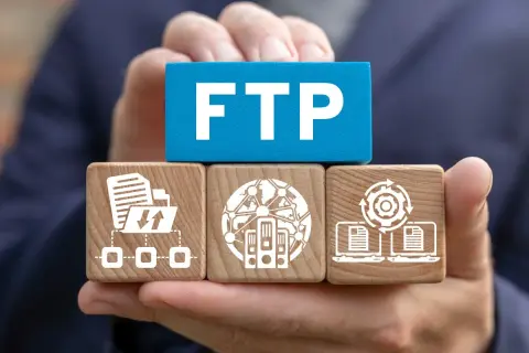 Dłonie trzymają kostki symbolizujące połączenie FTP: transfer plików, serwery w sieci i synchronizację danych.