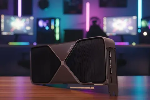 Najnowsza karta graficzna RTX 5090 na drewnianym blacie, w tle gamingowy setup z kolorowymi światłami RGB.