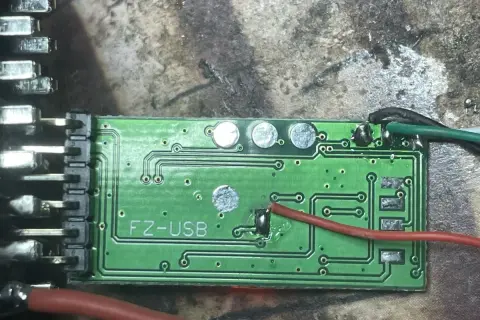 Zielona płytka drukowana z oznaczeniem "FZ-USB", prawdopodobnie moduł ELM327. Widać przewody i złącza, gotowe do instalacji sterowniki.