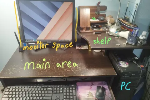 Biurko z monitorem 21 cali, PC, klawiaturą i półką. Na półce stoją ozdoby i drobne przedmioty.