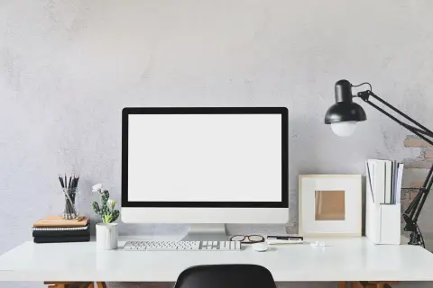 Nowoczesne biurko z monitorem, klawiaturą i lampką. Idealne miejsce do pracy zdalnej, gdzie pulpit zdalny pozwoli Ci połączyć się z biurem.