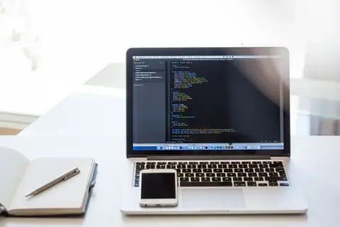 Laptop z kodem, telefon i notatnik. To może być przygotowanie do CTF, czyli Capture The Flag, gdzie rozwiązuje się zadania programistyczne.