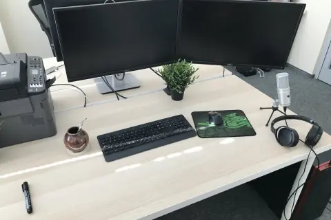 Biurko z dwoma monitorami, klawiaturą, myszką i słuchawkami. Idealne stanowisko do pracy jako programista.