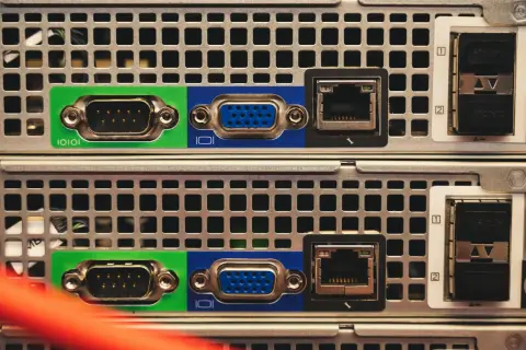 Zbliżenie na tylny panel dwóch serwerów, widoczne porty VGA, RJ45 i SFP. Trwa budowa serwera.