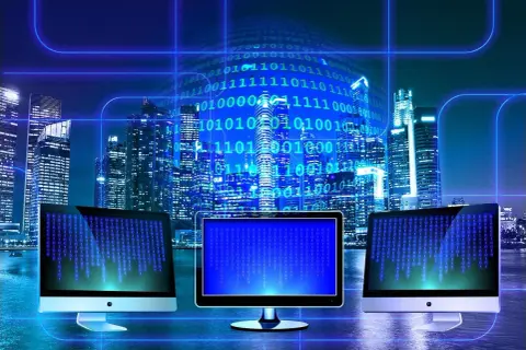 Trzy monitory wyświetlają kod binarny na tle nocnego miasta. W tle widać wieżowce i cyfrowy kod, symbolizujący technologię i sed linux.