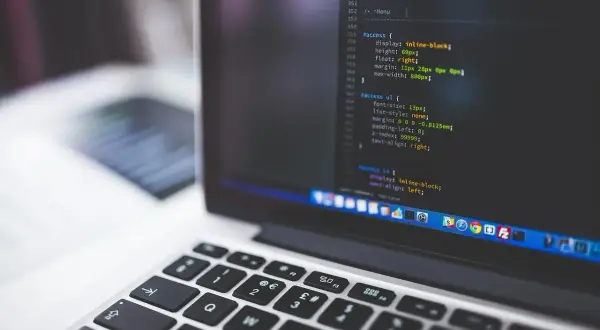 Kod źródłowy na ekranie laptopa, przypominający instalację linux snap. Widoczna klawiatura i fragment ekranu z kodem.