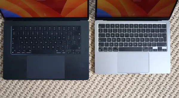 Dwa laptopy MacBook Air, jeden ciemny, drugi srebrny, leżą obok siebie. Ich niska waga sprawia, że są idealne do pracy w podróży.
