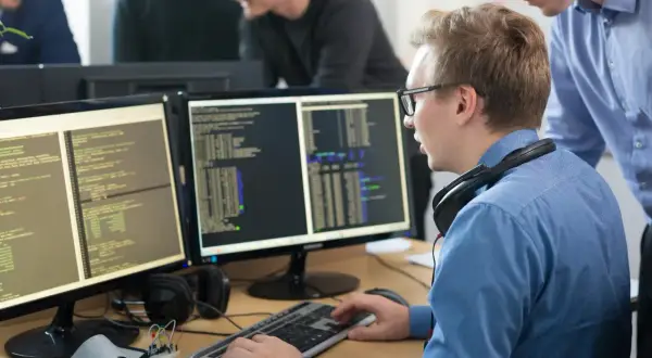 Programiści pracują nad kodem na monitorach, tworząc wolne oprogramowanie.