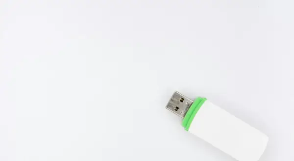 Biały pendrive z zieloną opaską, gotowy do podłączenia. Ten woe usb pomieści Twoje dane.