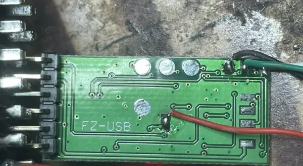 Zielona płytka drukowana z oznaczeniem "FZ-USB", prawdopodobnie moduł ELM327. Widać przewody i złącza, gotowe do instalacji sterowniki.