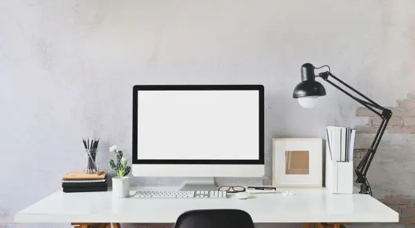 Nowoczesne biurko z monitorem, klawiaturą i lampką. Idealne miejsce do pracy zdalnej, gdzie pulpit zdalny pozwoli Ci połączyć się z biurem.