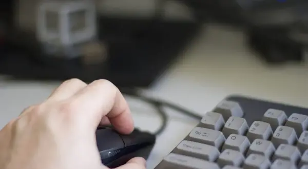 Dłoń steruje myszką na tle klawiatury i monitora. Użytkownik pracuje na systemie Linux, eksplorując jego możliwości.