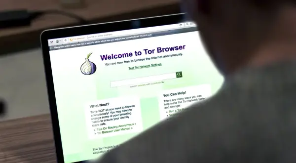 Osoba korzysta z laptopa z otwartą stroną powitalną przeglądarki **Tor Browser**, która umożliwia anonimowe przeglądanie Internetu.