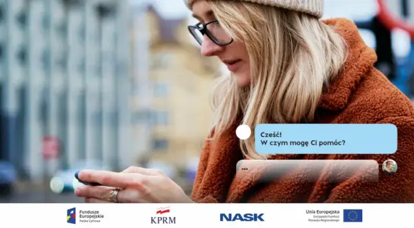 Kobieta z okularami patrzy na telefon, gdzie widać okienko czatu z pytaniem "Cześć! W czym mogę Ci pomóc?". To przykład, co to jest bot.