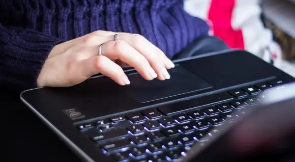 Dłoń na touchpadzie laptopa. Zwiększenie pamięci RAM w laptopie przyspiesza pracę, co daje płynniejsze działanie programów i gier.