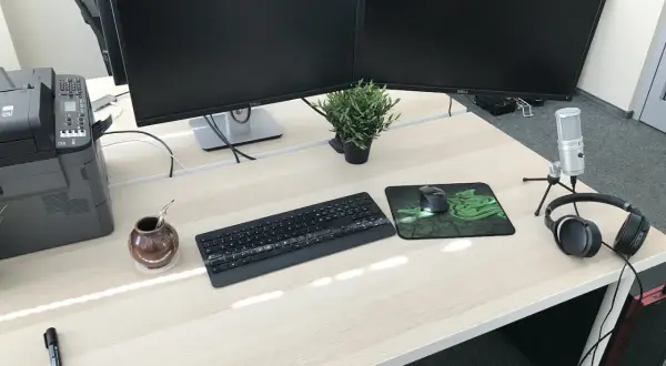 Biurko z dwoma monitorami, klawiaturą, myszką i słuchawkami. Idealne stanowisko do pracy jako programista.