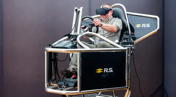 Mężczyzna w goglach VR przeżywa swoje **speed dreams** na symulatorze wyścigowym.