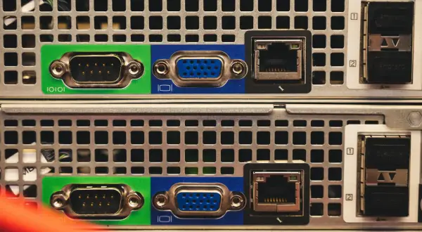 Zbliżenie na tylny panel dwóch serwerów, widoczne porty VGA, RJ45 i SFP. Trwa budowa serwera.