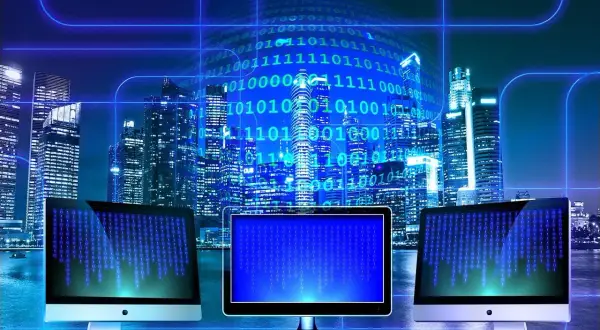 Trzy monitory wyświetlają kod binarny na tle nocnego miasta. W tle widać wieżowce i cyfrowy kod, symbolizujący technologię i sed linux.