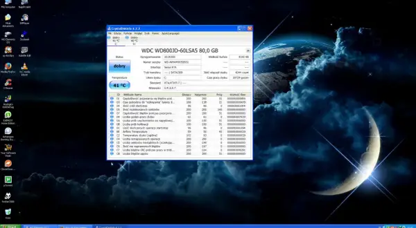 Na pulpicie systemu Windows z tapetą kosmiczną widać okno programu CrystalDiskInfo, który monitoruje stan dysku twardego. W tle, na pasku zadań, widoczny jest skrót do "Linux na starym kompu...", sugerujący, że system ten jest używany.