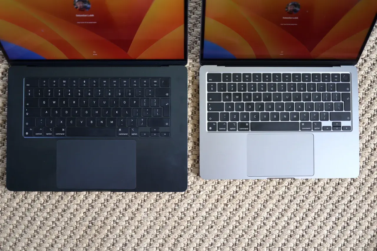 Dwa laptopy MacBook Air, jeden ciemny, drugi srebrny, leżą obok siebie. Ich niska waga sprawia, że są idealne do pracy w podróży.