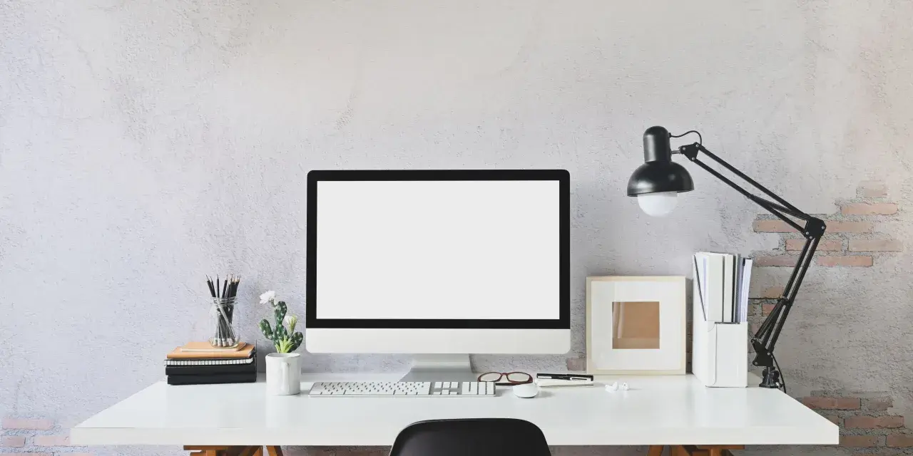 Nowoczesne biurko z monitorem, klawiaturą i lampką. Idealne miejsce do pracy zdalnej, gdzie pulpit zdalny pozwoli Ci połączyć się z biurem.