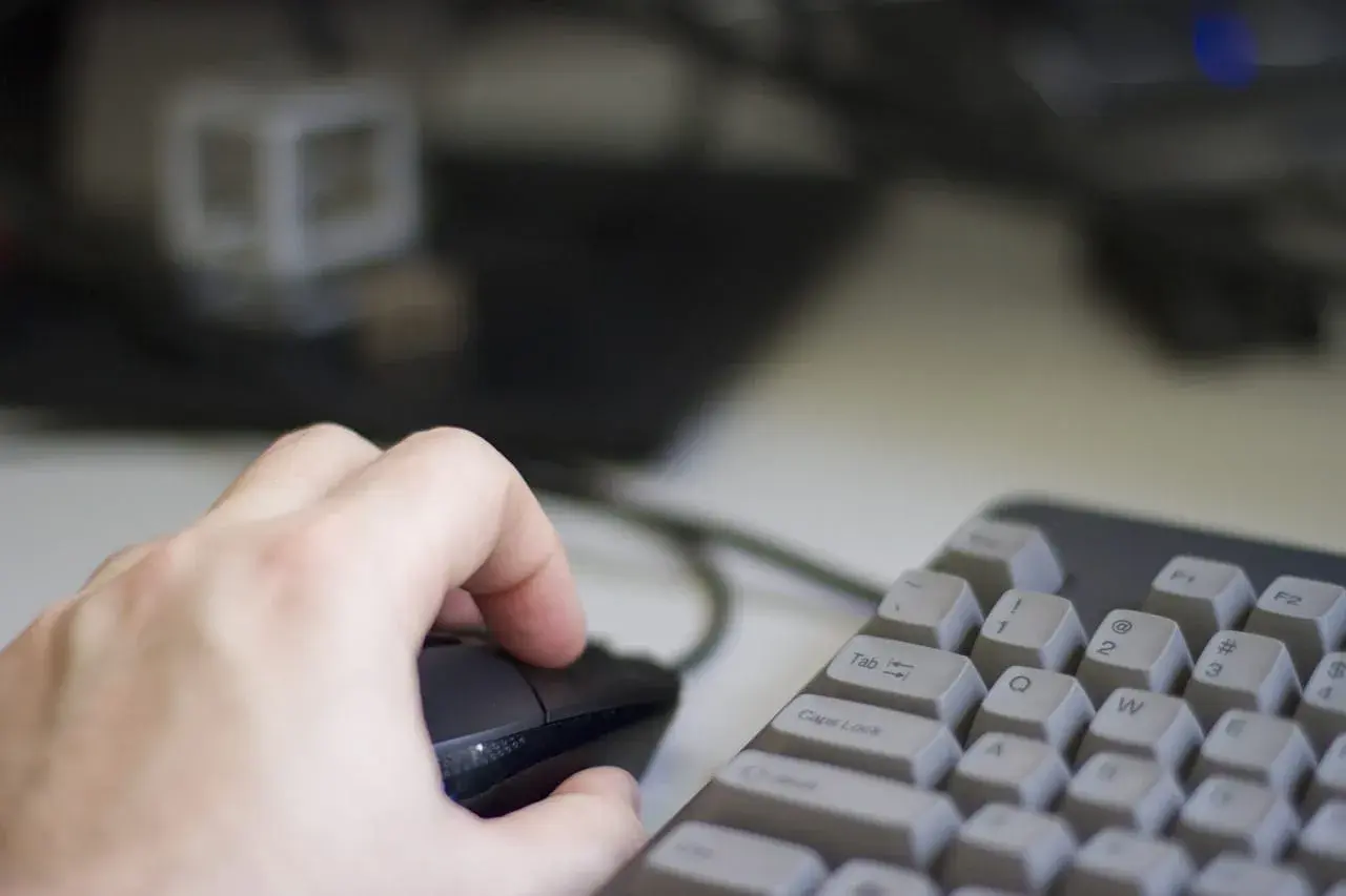 Dłoń steruje myszką na tle klawiatury i monitora. Użytkownik pracuje na systemie Linux, eksplorując jego możliwości.