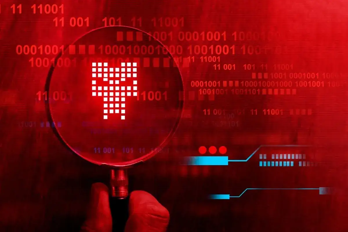 Pod lupą widać symbol wirusa, który wysyła smsy. Czerwone tło z kodem binarnym sugeruje zagrożenie cyfrowe.