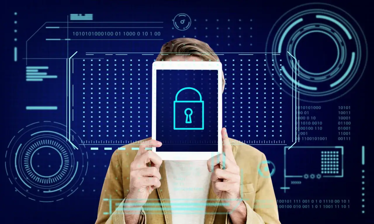 Mężczyzna trzyma tablet z ikoną kłódki, symbolizującą ochronę przed malware. Cyfrowe tło z kodem binarnym podkreśla bezpieczeństwo danych.