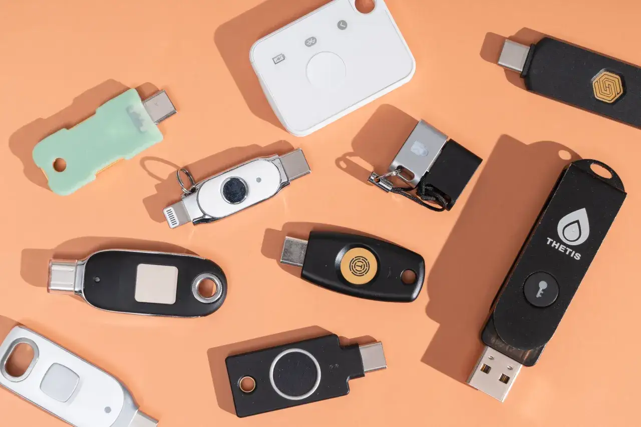 Klucze bezpieczeństwa USB i inne urządzenia do uwierzytelniania dwuskładnikowego leżą na pomarańczowym tle.