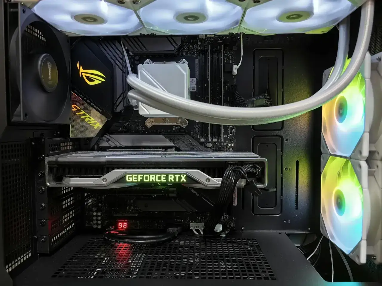 Wnętrze komputera z podświetlanymi wentylatorami i kartą graficzną GeForce RTX. Widoczne części komputera: płyta główna, chłodzenie wodne, GPU.