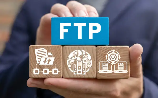 Dłonie trzymają kostki symbolizujące połączenie FTP: transfer plików, serwery w sieci i synchronizację danych.